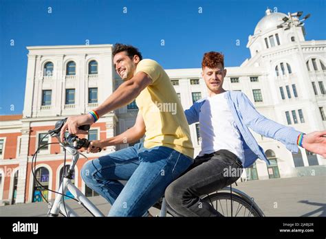 Young Gay Couple Enjoying A Bike Ride Together Outdoors Lgbt Young Gay Couple Enjoying A Bike Ride Together Outdoors Lgbt